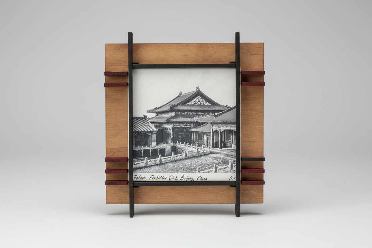 Wooden picture frame with a black and white photo of a building on a ceramic surface.